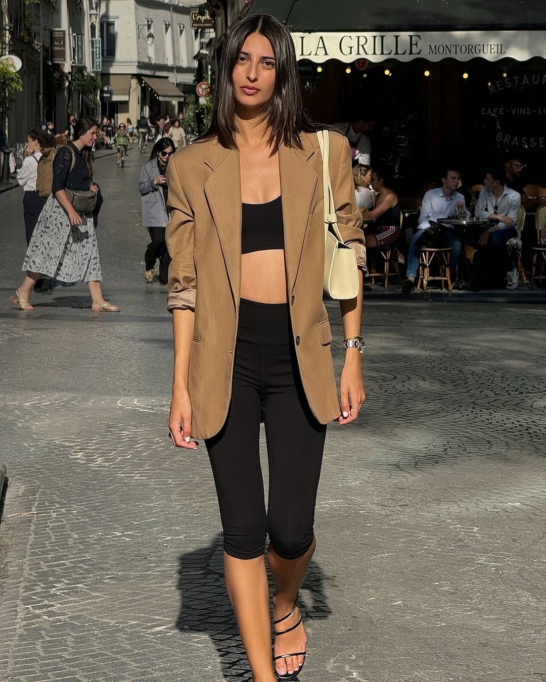 Influencer @salome.mory wears capri pants with a black crop top, oversized black and strappy sandals.