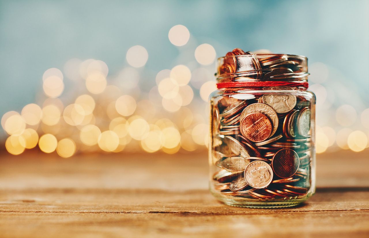 various types of U.S. coins in a jar on a wood surface against a background of blurred lights