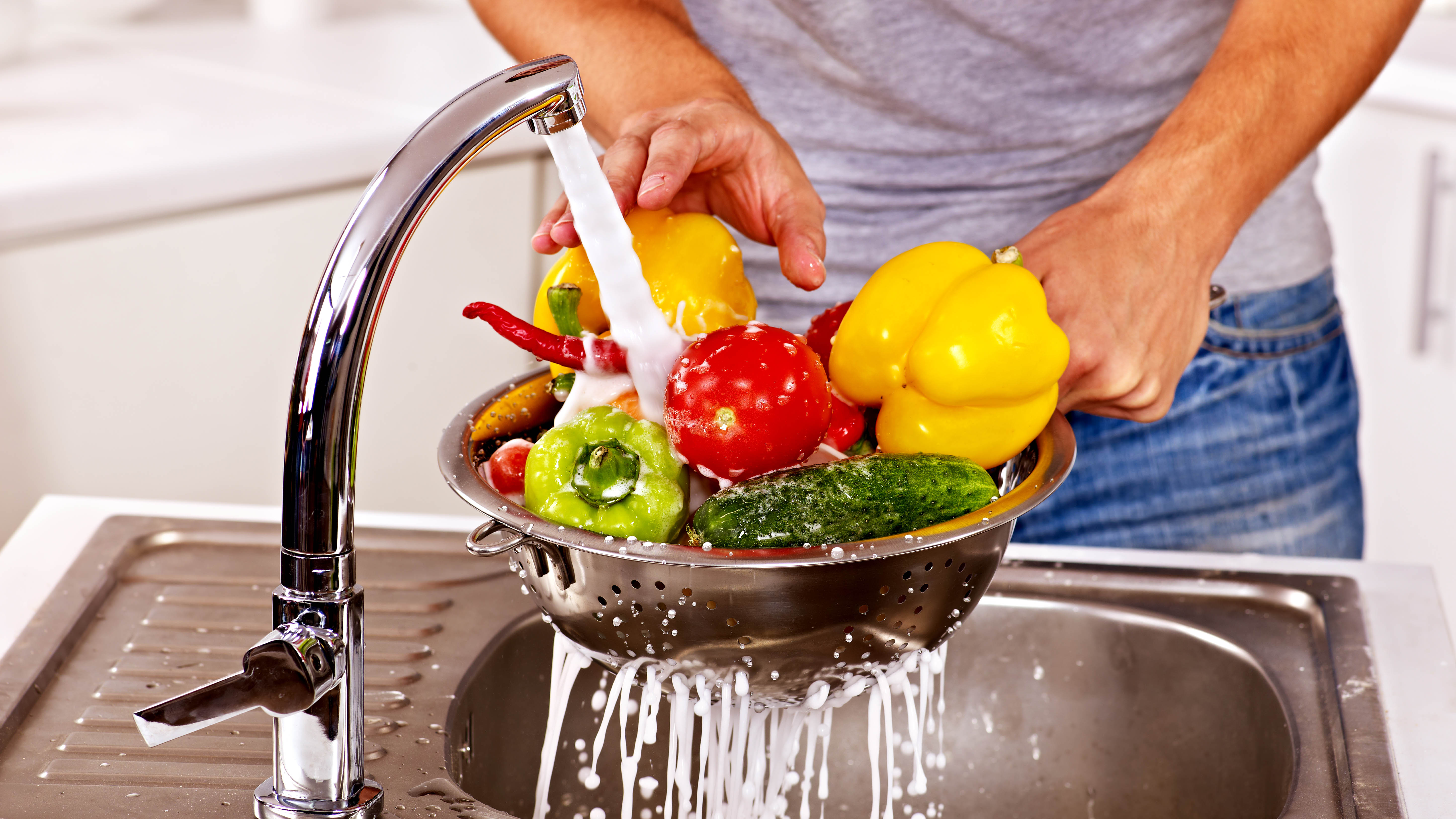 Washing bowl of fresh produce in sink