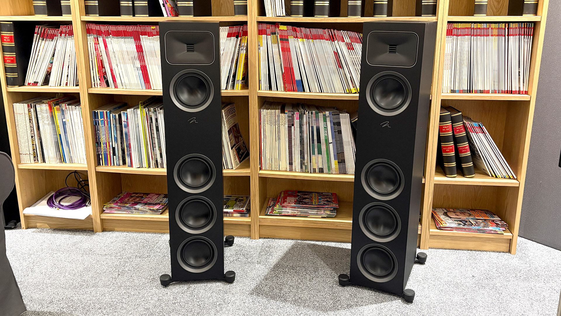 Martin Logan Motion Foundation F1 floorstanding speakers on grey carpet in front of bookcase
