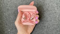 Shokz OpenFit Air, held in a hand wearing pink nail varnish