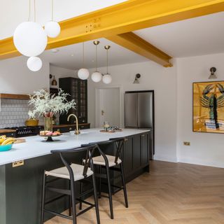 Open-plan kitchen with yellow steel beams and American-style fridge-freezer
