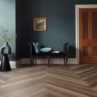 Hallway with teal walls, white skirting board and dark grain parquet wood effect LVT flooring