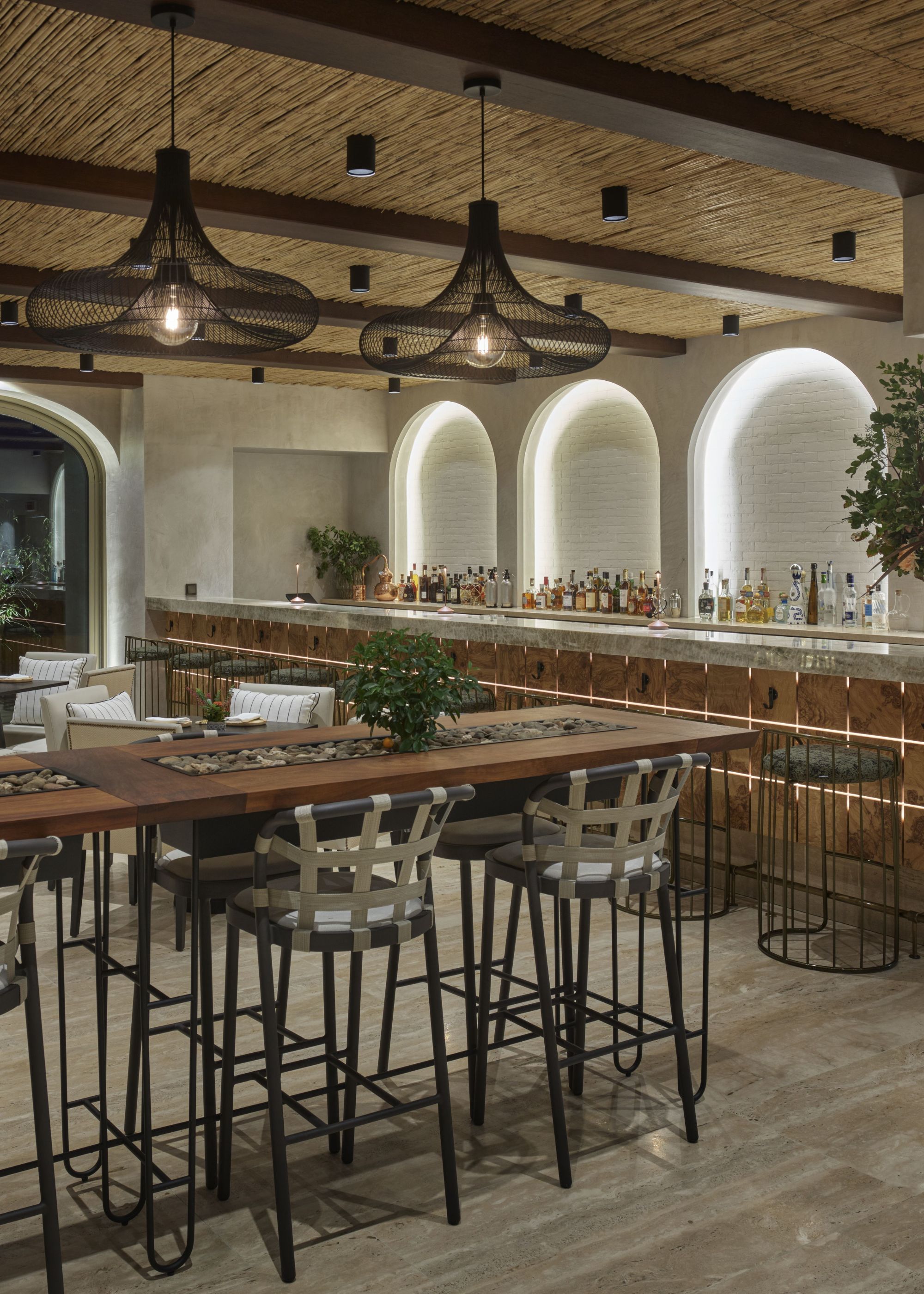 A bamboo ceiling kitchen with pendant lights hanging above the table and bar chairs. There is also a view of the bar.