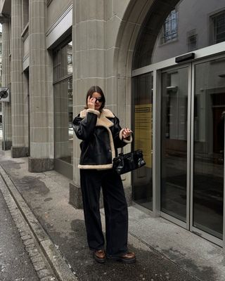 @maryljean wears a shearling jacket, black corduroy trousers, chunky brown shoes and a Prada bag