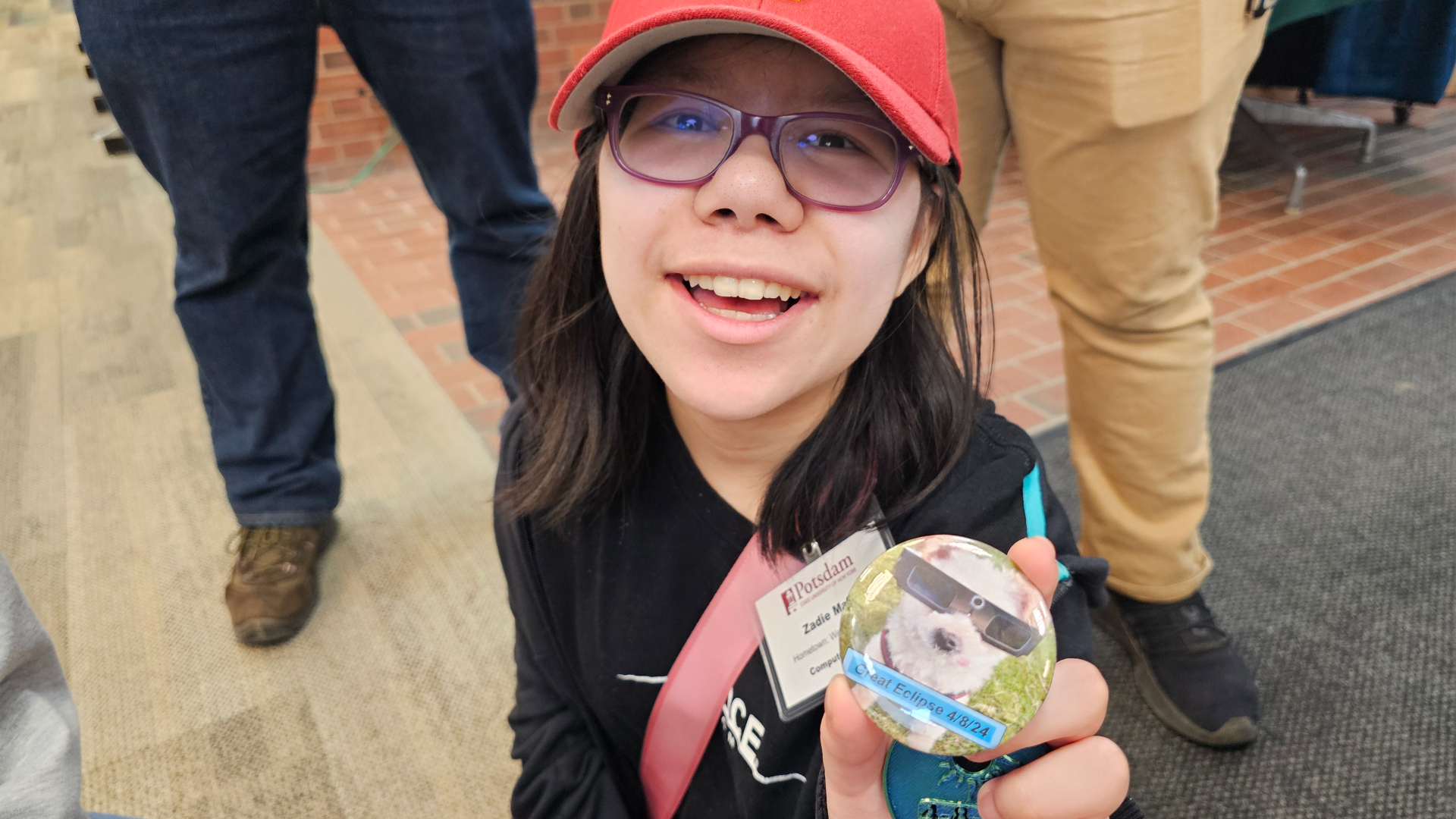 Zadie Malik shows off a Ted the Morale Officer solar eclipse button at SUNY Potsdam during the total solar eclipse on April 8, 2024.