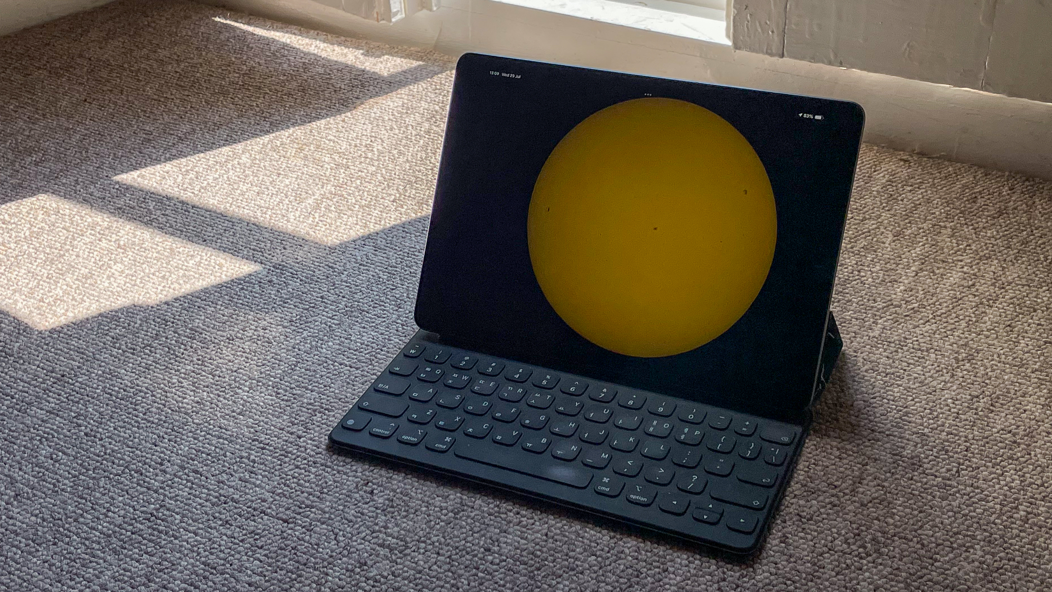 An iPad screen showing the solar disk from the Unistellar app against some shadowed carpet.