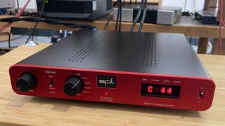 SPL Phonitor SE headphone amp on wooden hi-fi rack showing front panel and display
