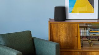 Harman Kardon Enchant Speaker on a side table next to a painting