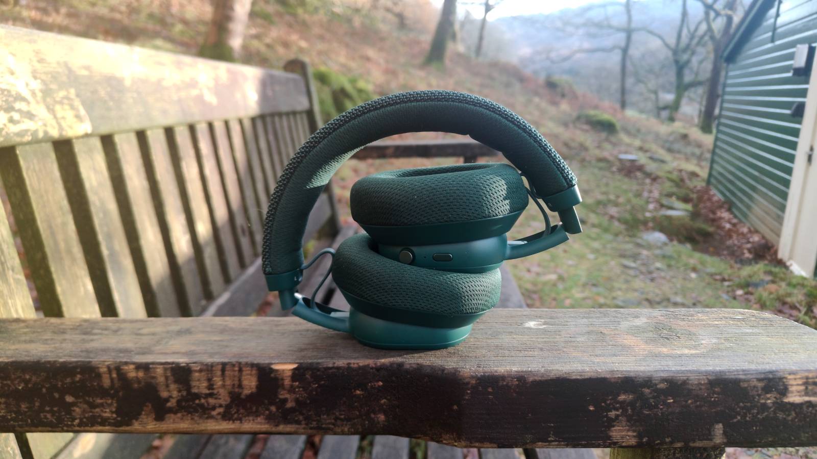 The Fairphone Fairbuds XL 2025 folded down on the arm of a bench.