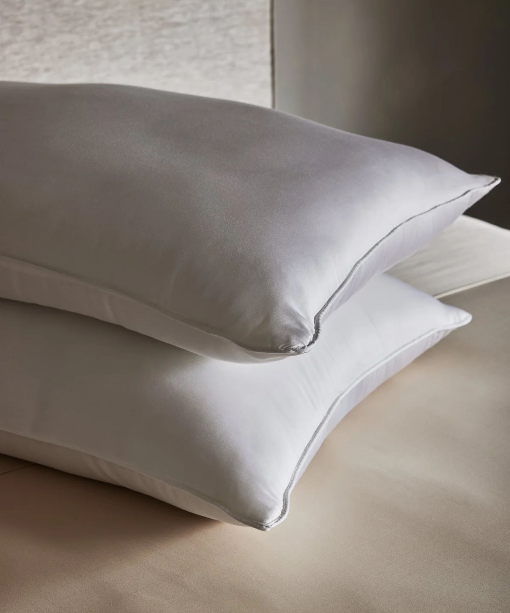 Two Brooklinen down alternative pillows stacked in a neutral bedroom