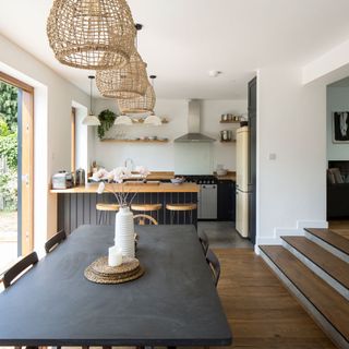 Black dining table in front of small kitchen with various appliances