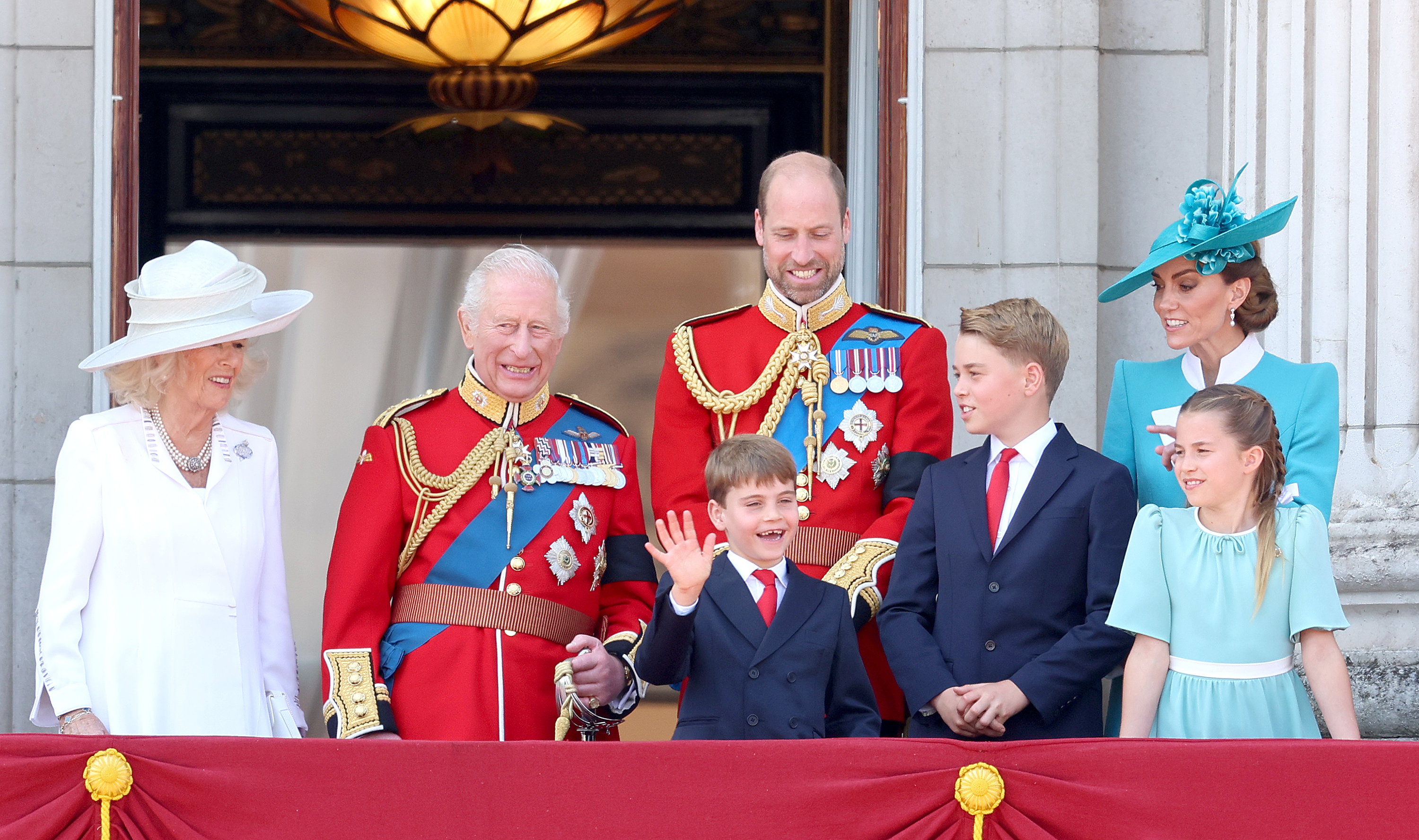 Prince Louis waving during Trooping the Colour standing with Prince William, Queen Camilla, Princess Kate and Princess Charlotte
