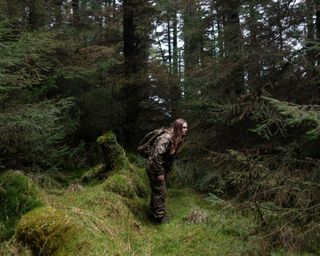 a person crouching in woodland