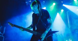 Greg Mackintosh plays his 7-string Habas live onstage with Paradise Lost, on a stage lit in pale blue and green lights.