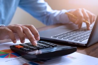 Female accountant using calculator and laptop