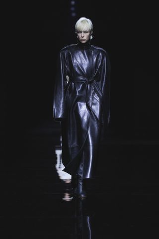 a khaite model wears a wrap leather trench coat on a dark runway in a celebrity style story