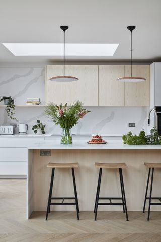 Kitchen with white and wood cabinets, island with bar stools, and pendant lighting