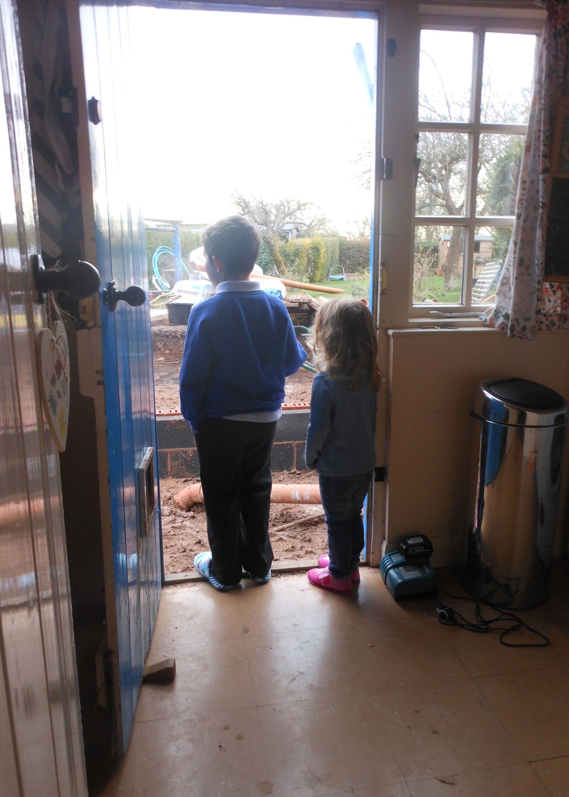two children standing in a doorway looking out to an extension project