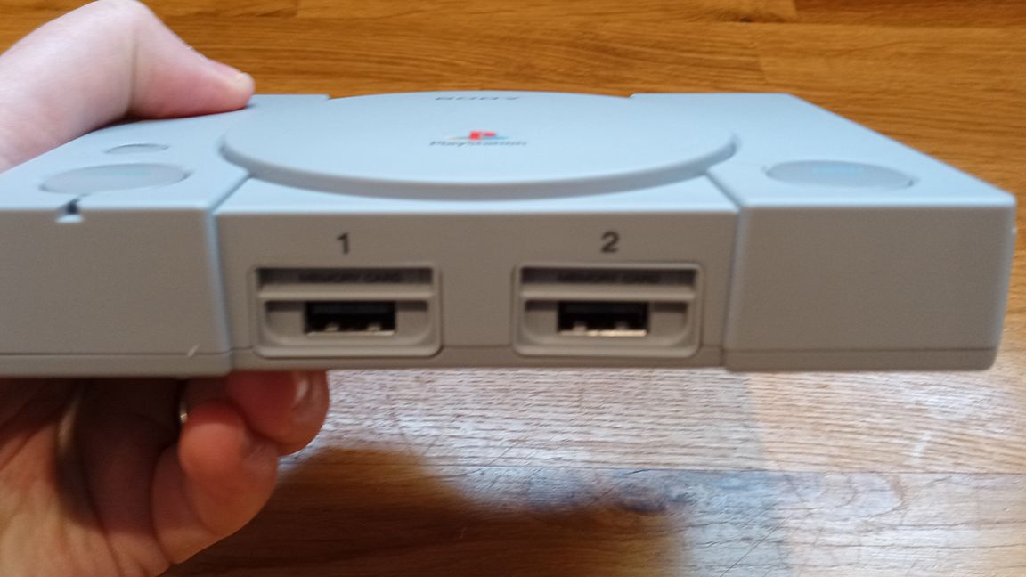 A photo of the front of the PlayStation Classic on a wooden table