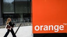 A woman walks next to the Orange logo in front of the Orange Group headquarters in Issy-les-Moulineaux, near Paris.