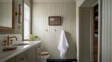 A country bathroom with paneled walls drenched in soft green