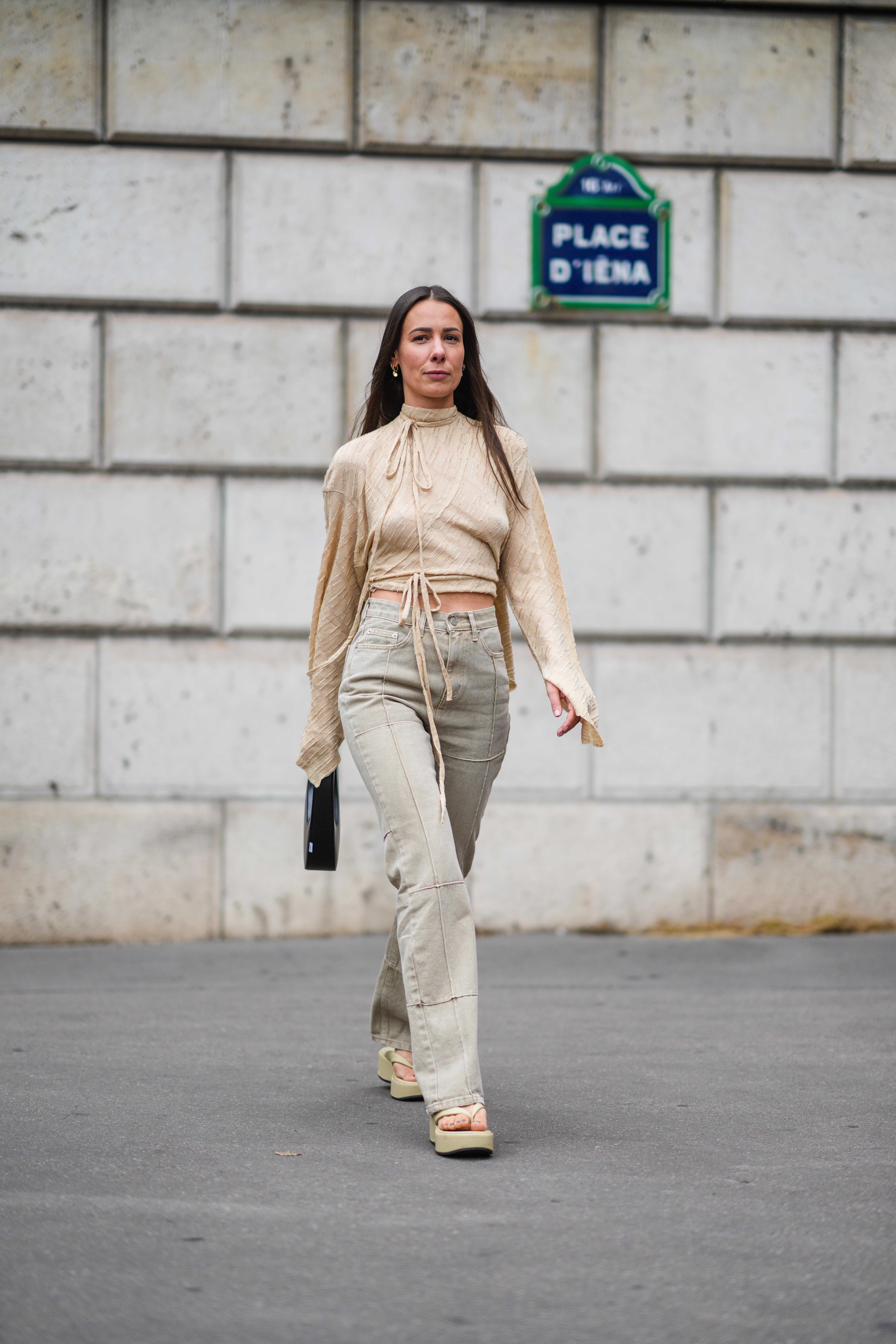 Alice Barbier wears a ripped turtleneck, jeans, pale yellow / beige matte leather flip-flops / sandals shoes during Paris Fashion Week