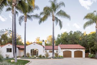 exterior of house with white walls and double garage and palm trees around