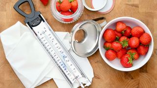 A food thermometer on a worktop beside some strawberries