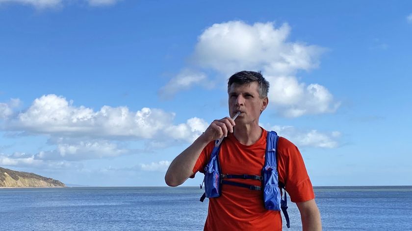 Runner drinking water from hydration pack on coast