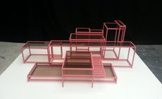 A pink metal shelf, with glass tops.