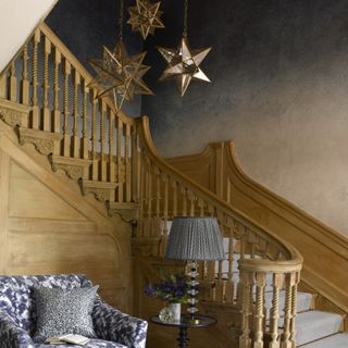 Star pendant lighting next to grey carpeted staircase with wooden banister