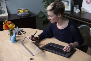 Woman using HP ZBook x2 as a tablet on a stand, with detached keyboard