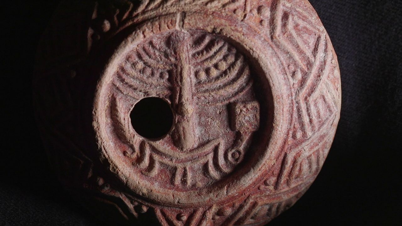 A close-up of a carved clay lamp