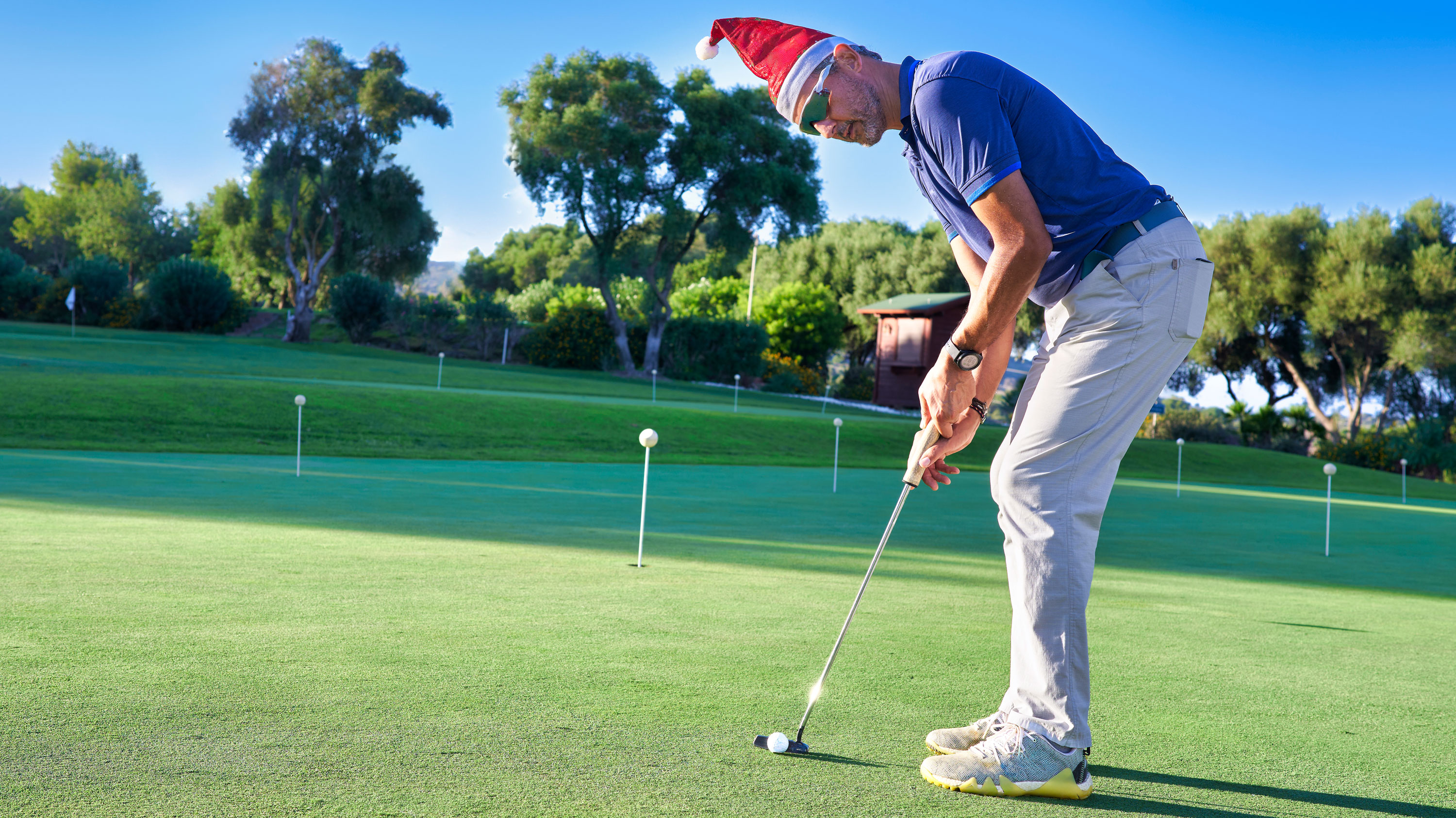 a golfer putts with a Christmas hat on