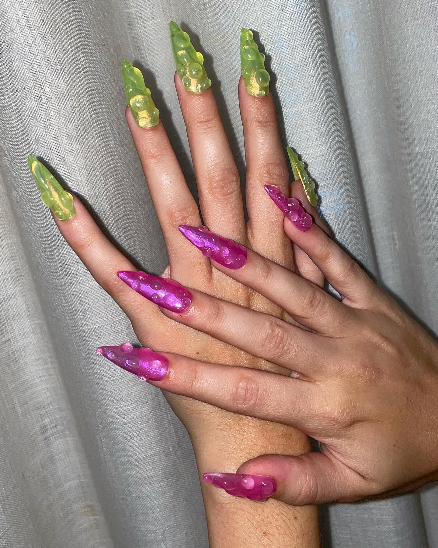 Charli XCX wearing green and pink jelly nails with water droplets on top.