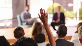 Audience member raises hand to question panel