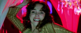 jessica harper as susie trying to stab someone against a pink backdrop in a still from suspiria