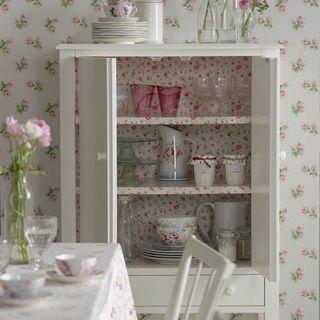 white cupboard with floral wallpaper and cutlery