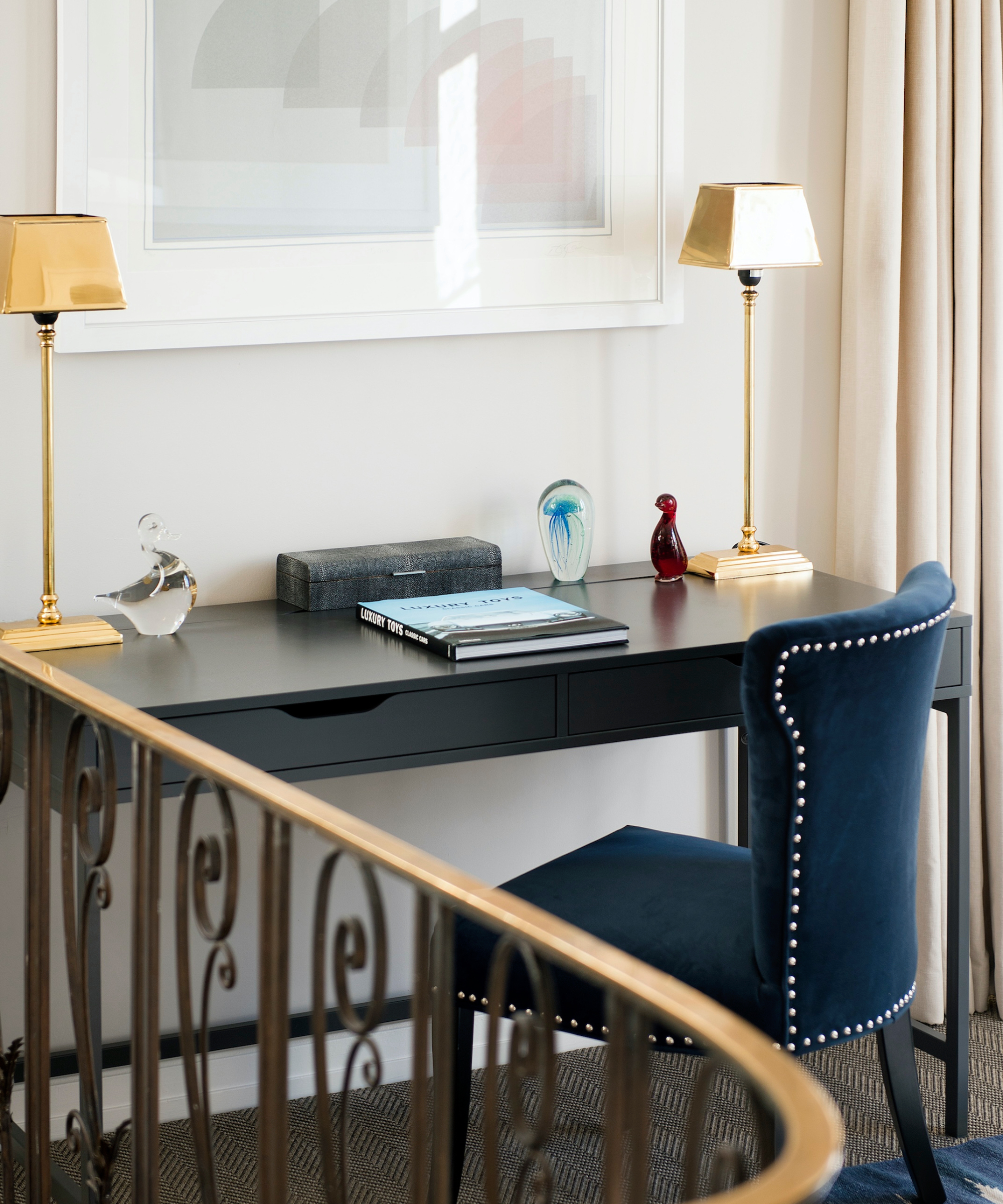 black desk and blue chair on landing area with artwork above