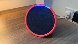 Amazon Echo Pop on a table, with a pink sleeve on
