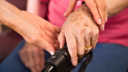 Close up of hands of nurse helping senior woman with her walker