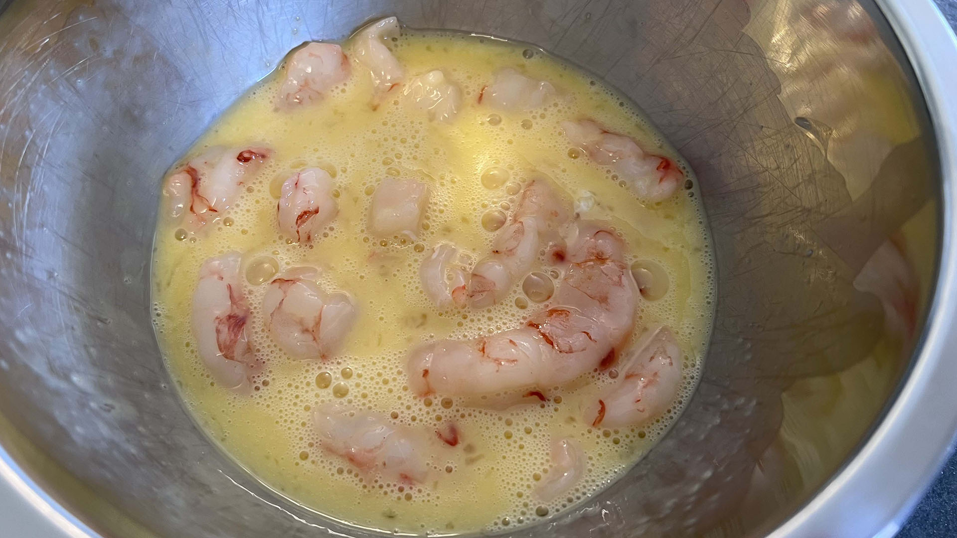 Raw shrimp in a bowl with beaten egg