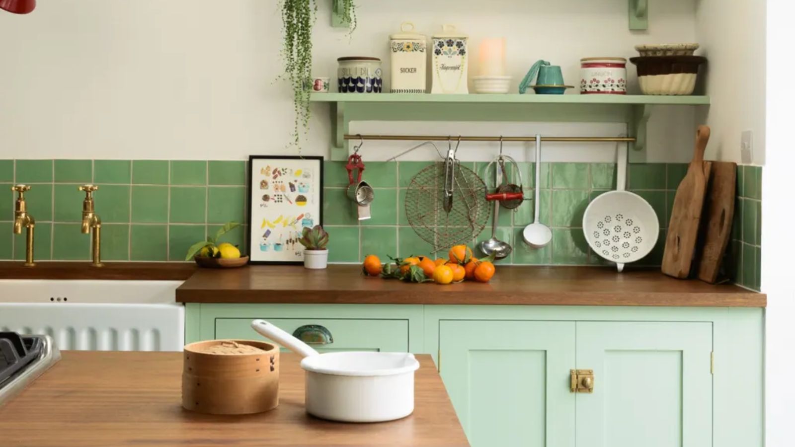 A Vintage kitchen with brown cabinets, a marble countersplash, a brass pot rack on the wall, and a range cooker topped with a vintage copper teapot