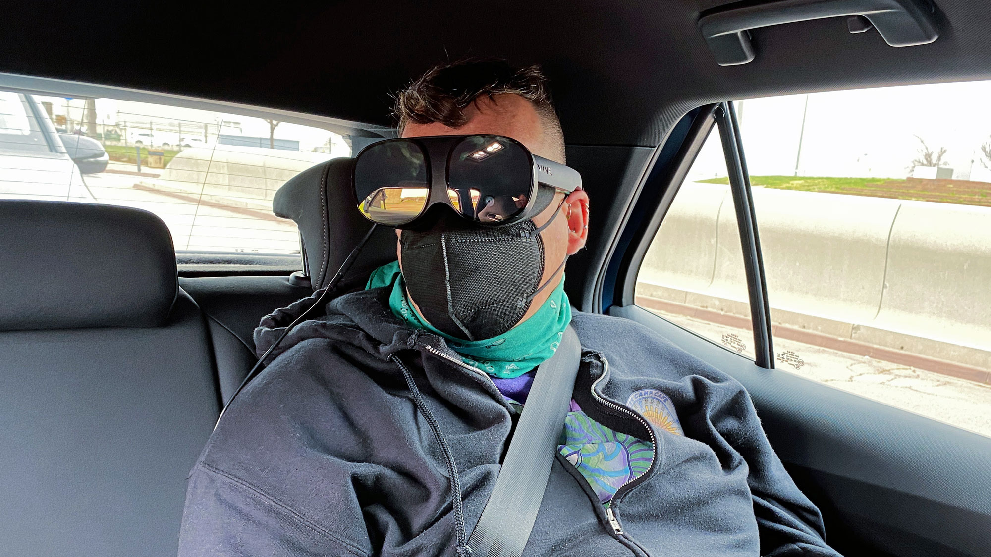 Woman sitting in rear seat of car wearing a VR headset