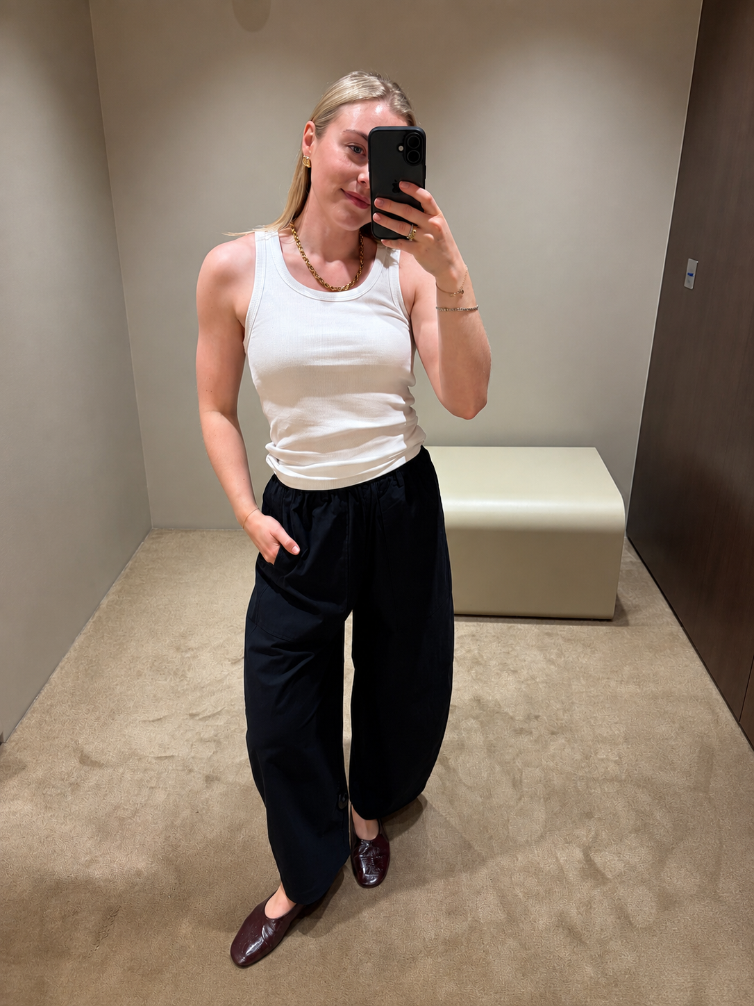 Woman wears white tank top, navy barrel leg linen trousers from COS and burgundy ballet flats