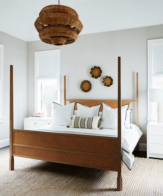 Bedroom with round wall art, large rattan pendant, wooden bed frame, and white bedding