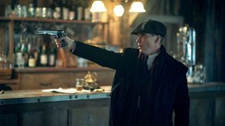 Tommy Shelby i Peaky Blinders med en pistol i hånden på en bar