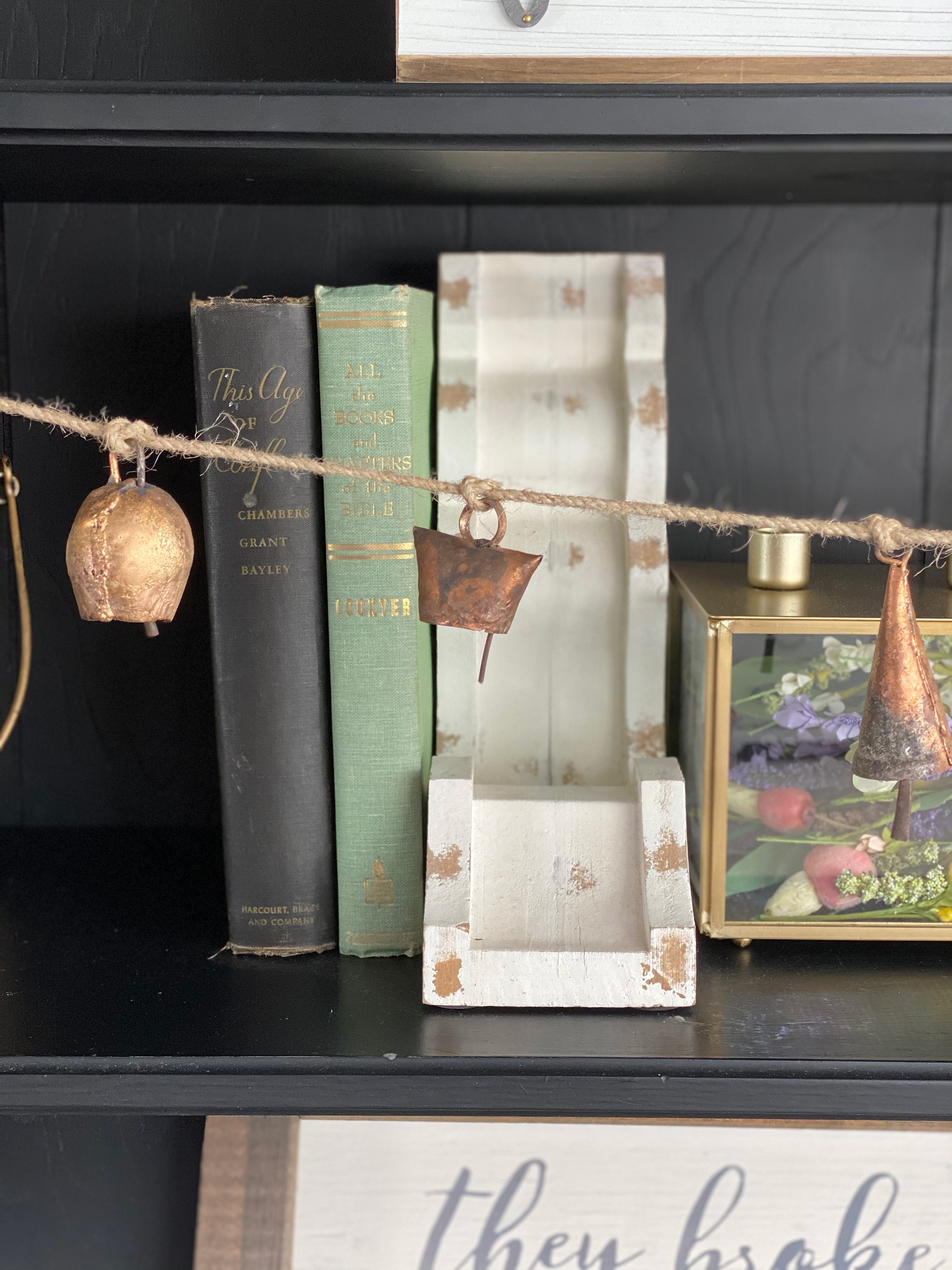 Hutch with decorative brass garland in front of shelving