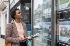 Woman looking at house prices at an estate agent window